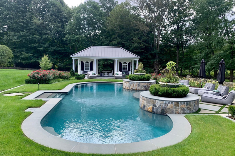 Exquisite outdoor swimming pool embraced by lush natural surroundings, crafted with luxury pool materials for an unparalleled aesthetic.