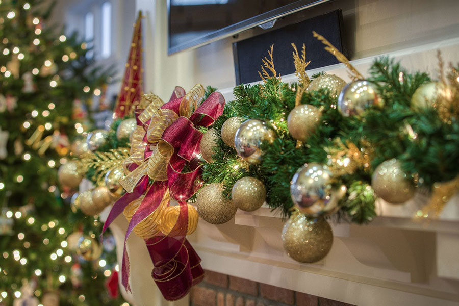 Close-up view of sparkling Christmas balls adorning the fireplace mantel, with a beautifully decorated Christmas tree in the background. 