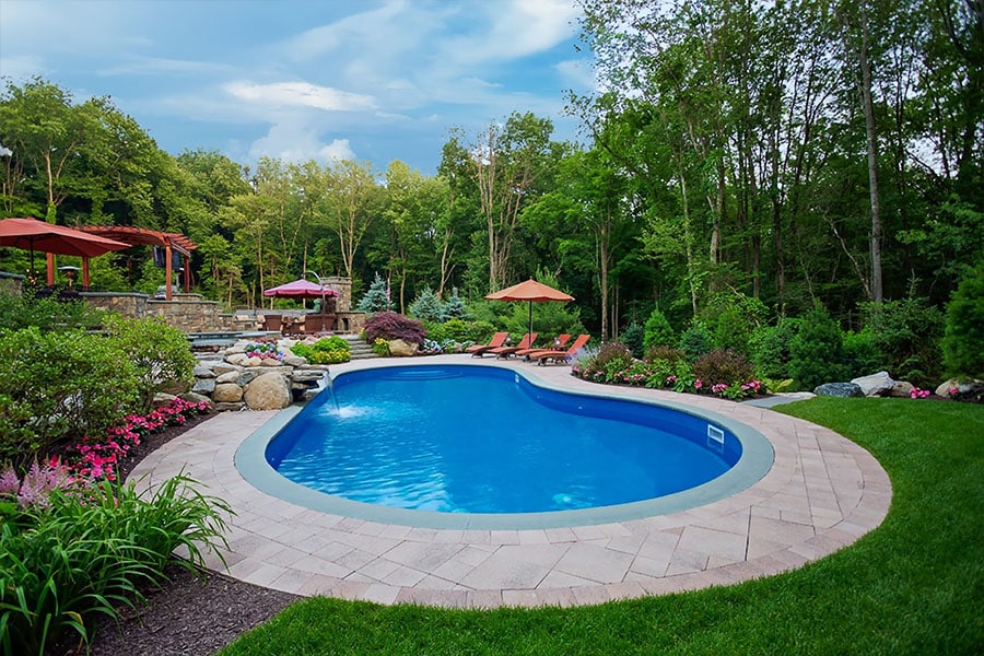 A serene pool nestled within a breathtaking landscape designed by our pool landscaping and lighting services in NY, NJ and CT