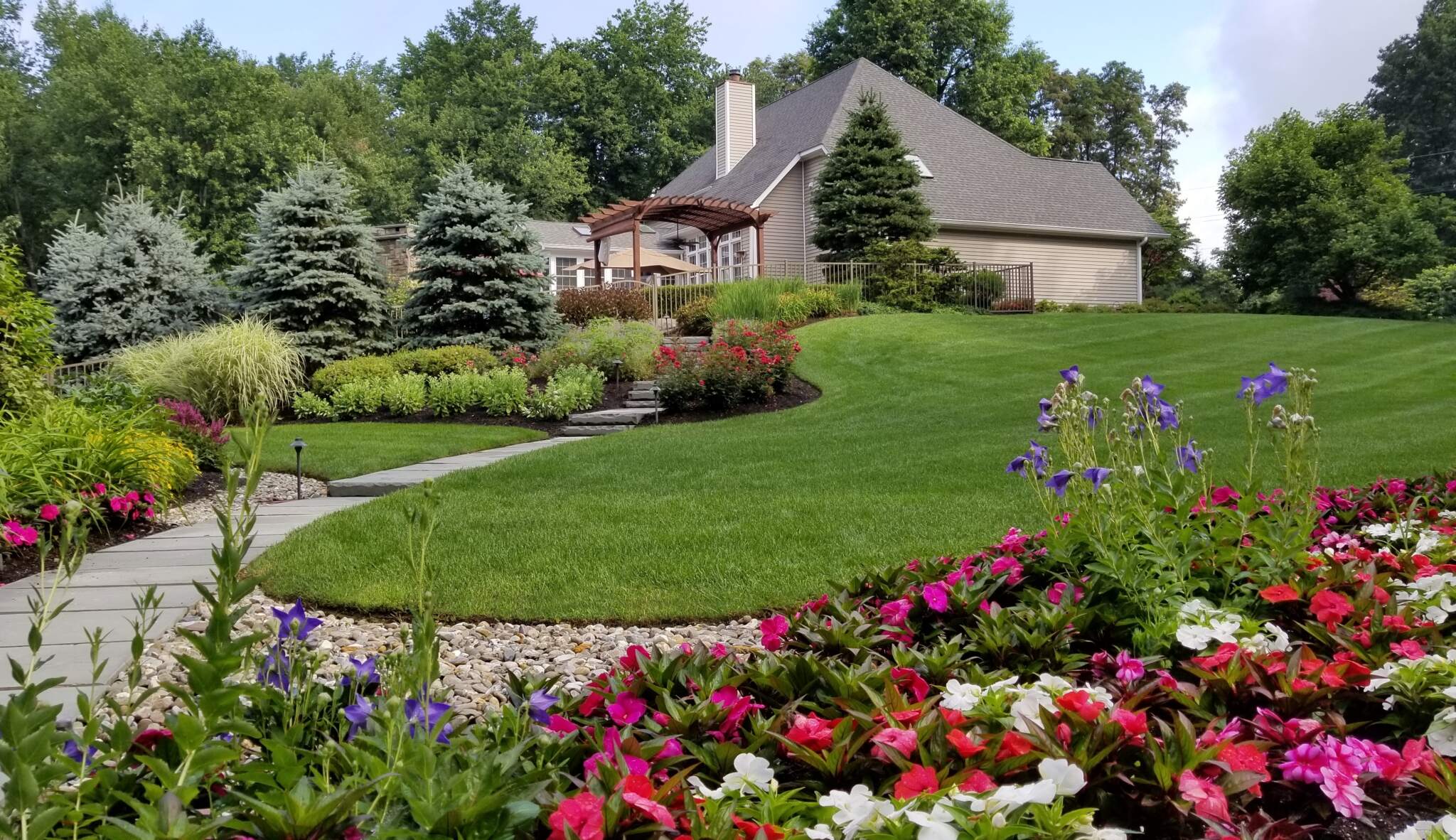 20170711_085824_Retouched A well-maintained lawn is separated from the garden by a curving edge of smooth river rocks using techniques to manage stormwater